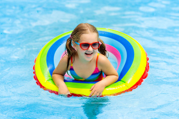 Child in swimming pool on toy ring. Kids swim.