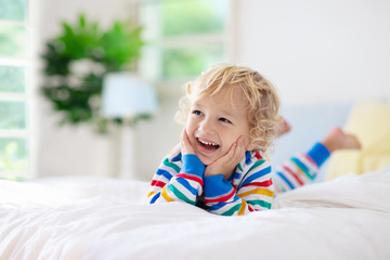 Child playing in bed. Kids room. Baby boy at home.