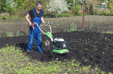 Fototapeta na wymiar Man working in the spring garden with tiller machine