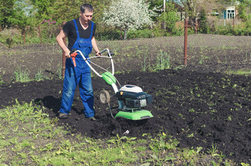 Man working in the spring garden with tiller machine