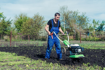 Man working in the spring garden with tiller machine