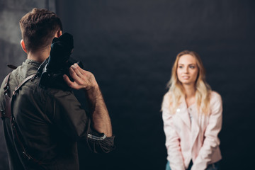 young talented photographer making up a pose for a good looking female client, creative shot, close up photo. back view photo, blurred background