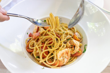 Woman eating spaghetti with fork. Spaghetti shrimp scampi with garlic,olive oil and chili. 