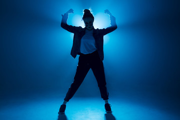 Fototapeta na wymiar Stylish woman dancing solo on hip hop party. Sunglasses, modern black dance wear, neon lights.