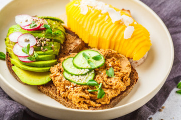 Vegan sandwiches with mango, avocado and tofu pate on a white plate.