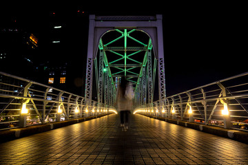 夜の天王洲のふれあい橋を渡る女性の後姿