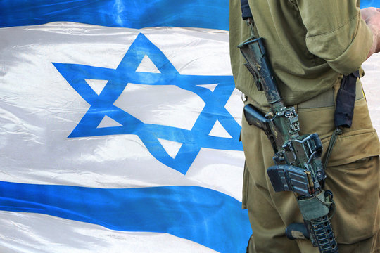 Soldier of Israeli defense forces. Israel National flag waving in the background 