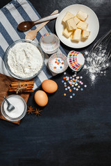 Fototapeta na wymiar Bakeware baking, fresh ingredients and cookies on a black background. Flat lay bakery text image space