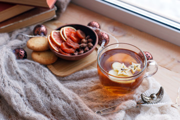 Cup of tea, snacks, book and warm blanket on windowsill, close up, relax unplug background, seasonal homely weekend, love to read concept