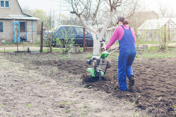 Young girl working in a spring garden with a cultivator