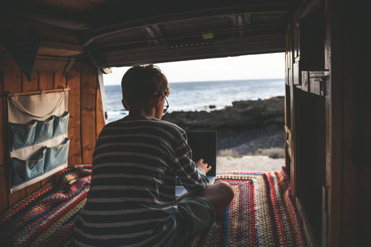 Young boy legs crossed on retro mini van transport Life inspiration concept with family on minivan adventure trip watching laptop pc. Student doing homework camping holiday with parents. Always online
