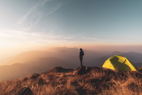 Young man traveler looking landscape at sunset and camping on mountain, Adventure travel lifestyle concept