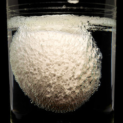 concept white egg covered with bubbles in glass with vinegar close-up