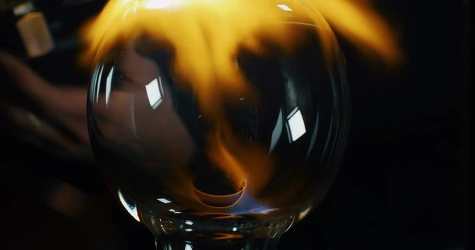 Slow motion of experienced glass blower working with flame on a handmade art piece of glass from precious crystal in a workshop.Shot in 8K.Concept of handmade,quality,artisan, made in Italy,glass blow