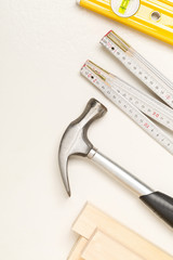 Construction tools and wooden strips on white plaster background