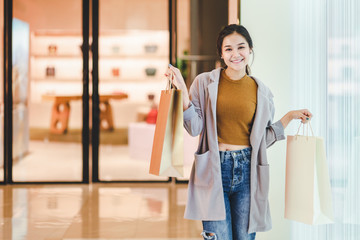 Lifestyle shopping concept, Young happy asian woman with paper bag and coat in shopping mall, vintage style