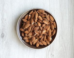 Healthy food  for background image close up almond nuts. Texture on white grey table top view. Nut on the cup plate