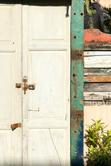 An old closed rustic wooden front door with a rusty lock