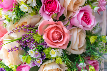 Background of beautiful fabric made white, green, peach, and pink roses and leaves. Selective focus of nature background