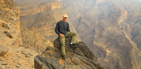 Wanderer macht Rast auf Felsen, Oman