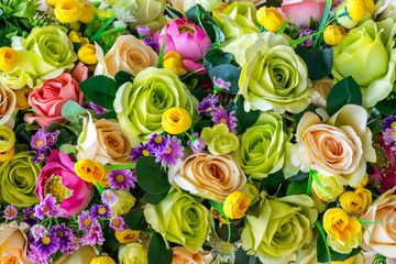 Background of beautiful fabric made white, green, peach, and pink roses and leaves. Selective focus of nature background