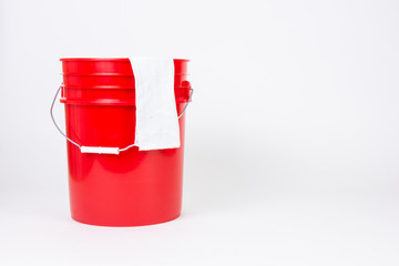 Isolated red bucket with wash cloth on white background. © Brian