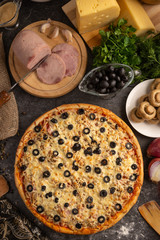 Pizza with ham, mushrooms, black olives and onions