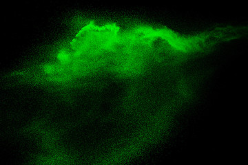 Green dust particles explosion on black background. Color powder dust splash.