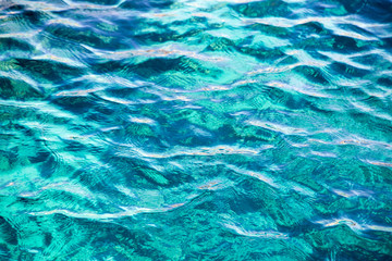 Coral reef is visible through the clear blue water. Beautiful blue sea wave photograph close up. Beach vacation at sea or ocean. Background to insert images and text. Tourism, travel.