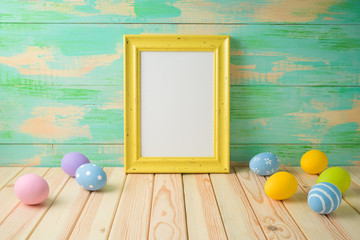 Photo frame or artwork display mock up on wooden table with easter eggs.