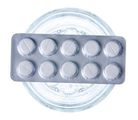 Glass of water with blister pills medecine on white background isolation, top view