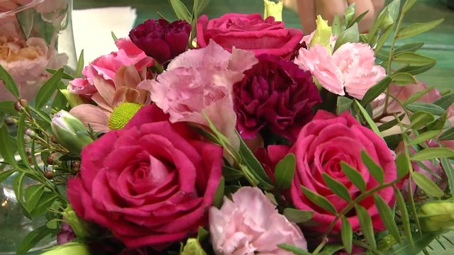 Video filming with hands without stabilization. Bouquet of colorful roses and other flowers at the entry to flower shop at farmers' market. Everyday flowers counter with variety of fresh cut flowers. 