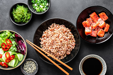 poke bowl ingredients - brown rice, trout or salmon fillet, Chuka Seaweed Salad, sesame and fresh vegetables, top view, healthy food trend