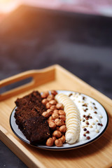 Closeup of healthy Breakfast plate with yogurt with chocolate chips, banana, rye bread and hazelnut