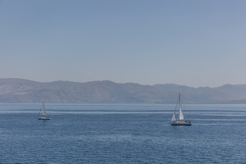 Idyllic landscape with two sailboats cruising a calm sea on summer