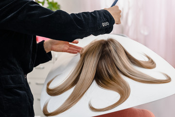 hairdresser makes hairstyle, dye on special disk at a beauty salon. Hair covered in dye