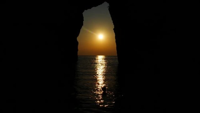 San Nicola Arcella, Cosenza, Calabria, Italy - September 6 2018: silhouette of bather in Arcomagno (Arco magno) at sunset, beautiful Italian beach an natural arch on Mediterranean sea (Tyrrhenian)