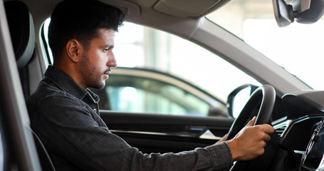 Fototapeta premium Young man examining a new car in a showroom