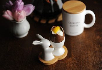 Easter dessert chocolate eggs filled with cream imitating white and yolk. Served on holder with Easter bunny