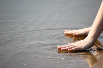 Girl hands touches the water in the river