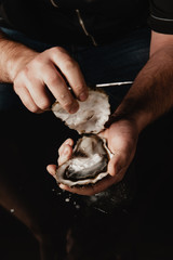hands open the oyster with a knife - 257066886