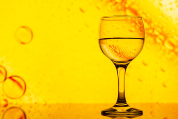 ransparent glasses with water with oily drops on colorful background 