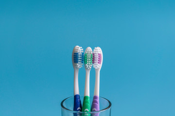 Set of toothbrushes in glass on blue background. Cup with toothbrushes against color background. Dental care