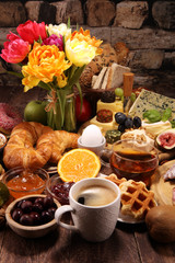 breakfast on table with bread buns, croissants, coffe and eggs
