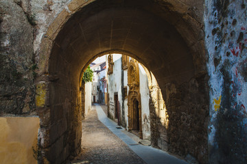 Fototapeta na wymiar pedestrian street trough the arch in Coimbra, Portugal