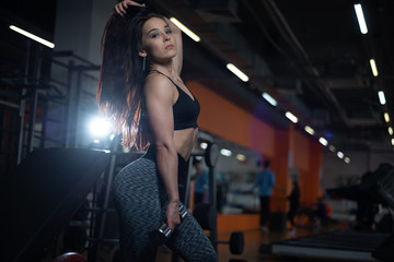 Obraz na płótnie Canvas Fitness girl trains biceps with dumbbells in the gym.