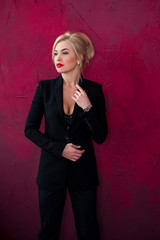 Woman in classical sexy black pantsuit , posing on red background. Concept of fashionable clothes 