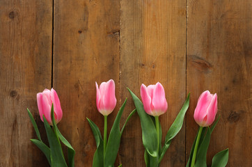 Obraz na płótnie Canvas bouquet of pink tulips over wooden background. Top view