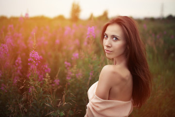 Fototapeta na wymiar beautiful woman with brunette hair in light clothes posing in flower field on background