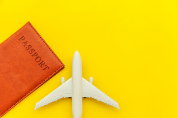 Travel by plane vacation summer weekend sea adventure trip journey ticket tour concept. Minimal simple flat lay with plane and passport on yellow trendy modern background. Tourist essentials